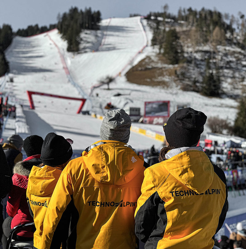 Collaborateurs TechnoAlpin en vestes jaunes devant piste de Coupe du Monde de ski