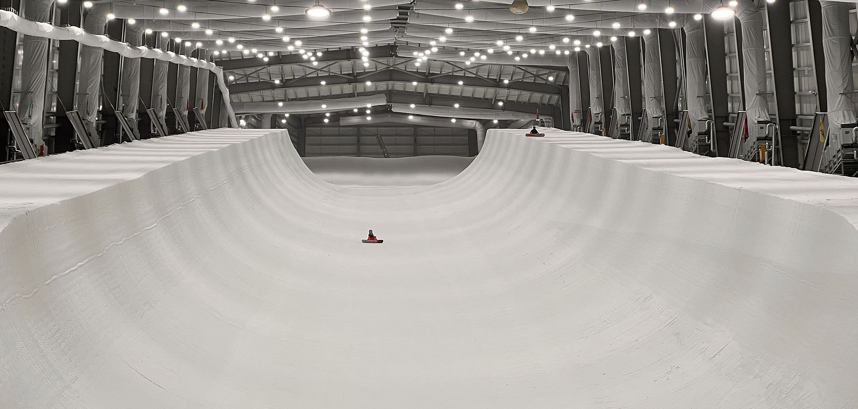 Salle de ski interieure avec piste half-pipe et surfeur sur bouee sous eclairage artificiel en Chine