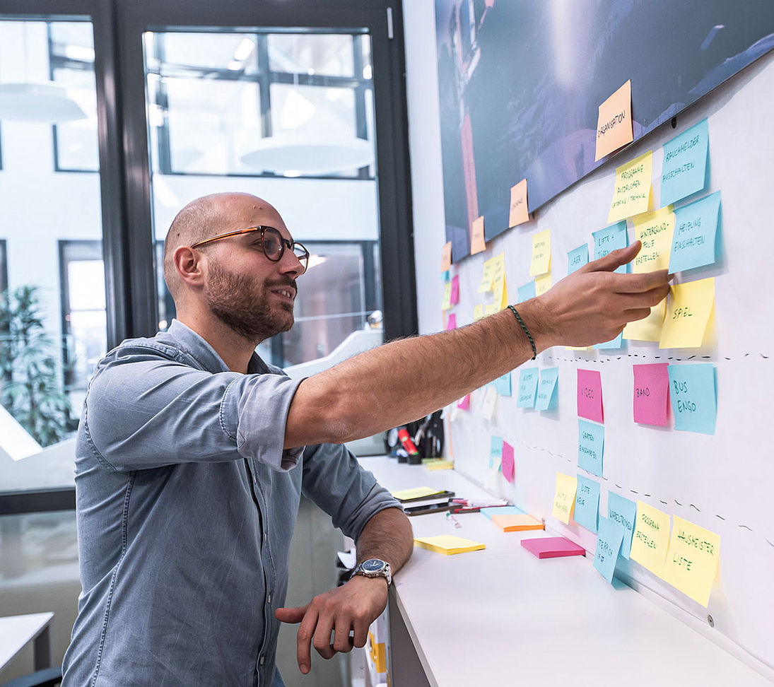 TechnoAlpin Mitarbeiter beim Brainstorming mit bunten Haftnotizen an der Planungstafel