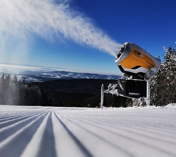 Cannone da neve TechnoAlpin TR8 su pista battuta con ampio panorama montano