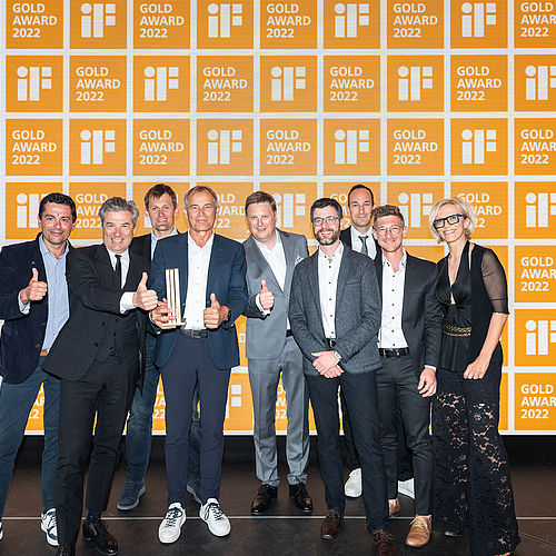Team TechnoAlpin con trofeo iF Gold Award 2022 su palco arancione illuminato con pollici su