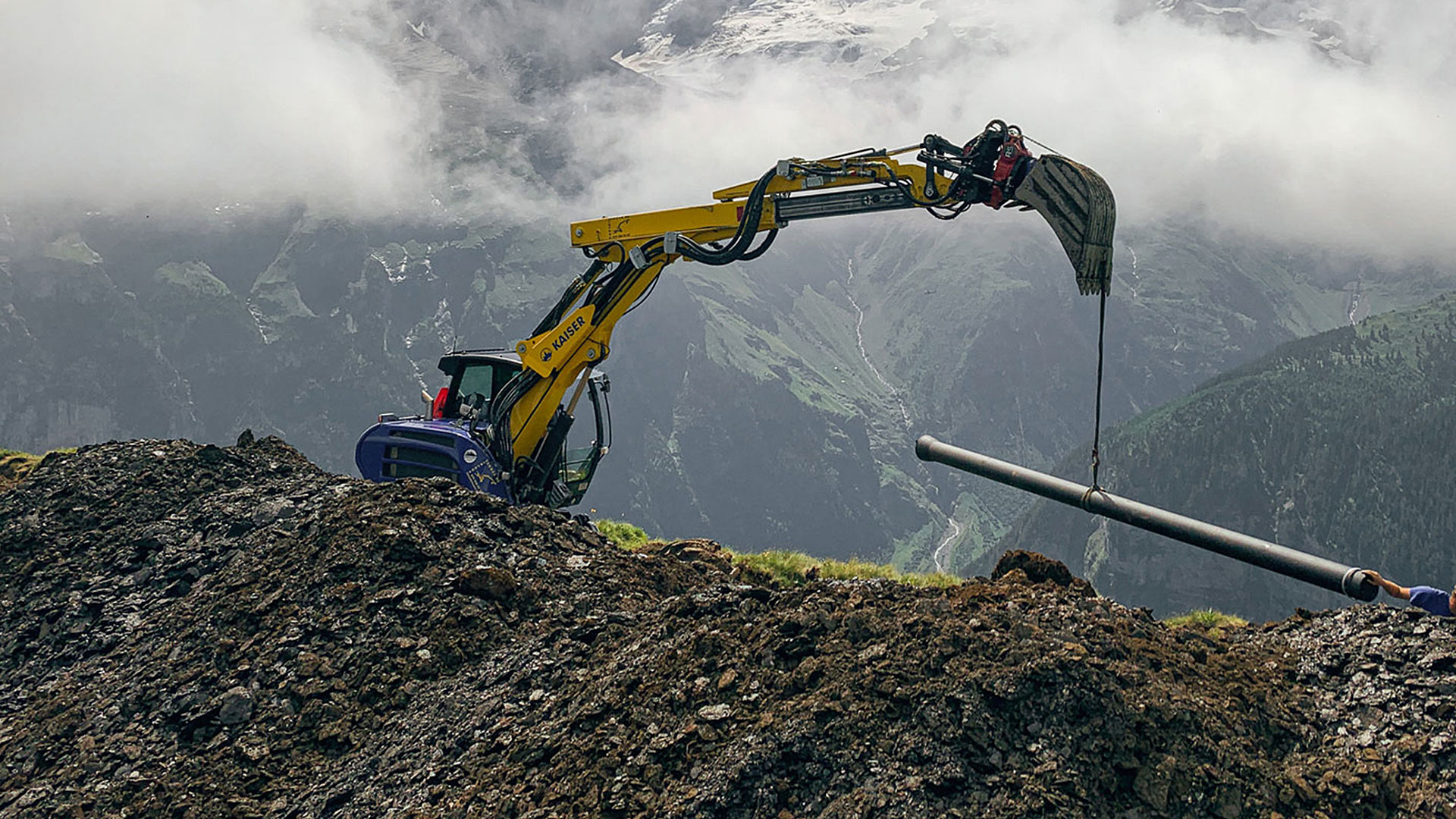 Bagger verlegt Rohrleitungen für Beschneiungsanlage im hochalpinen Gelände mit Bergblick
