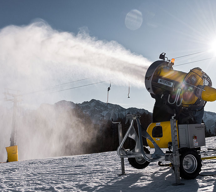 Mobile TechnoAlpin Propellerschneekanone beschneit Skipiste mit Bergpanorama