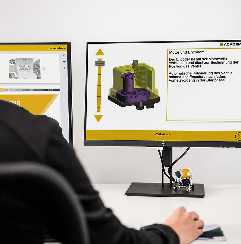 Person at desk with two screens and Academy training on valve motor and encoder