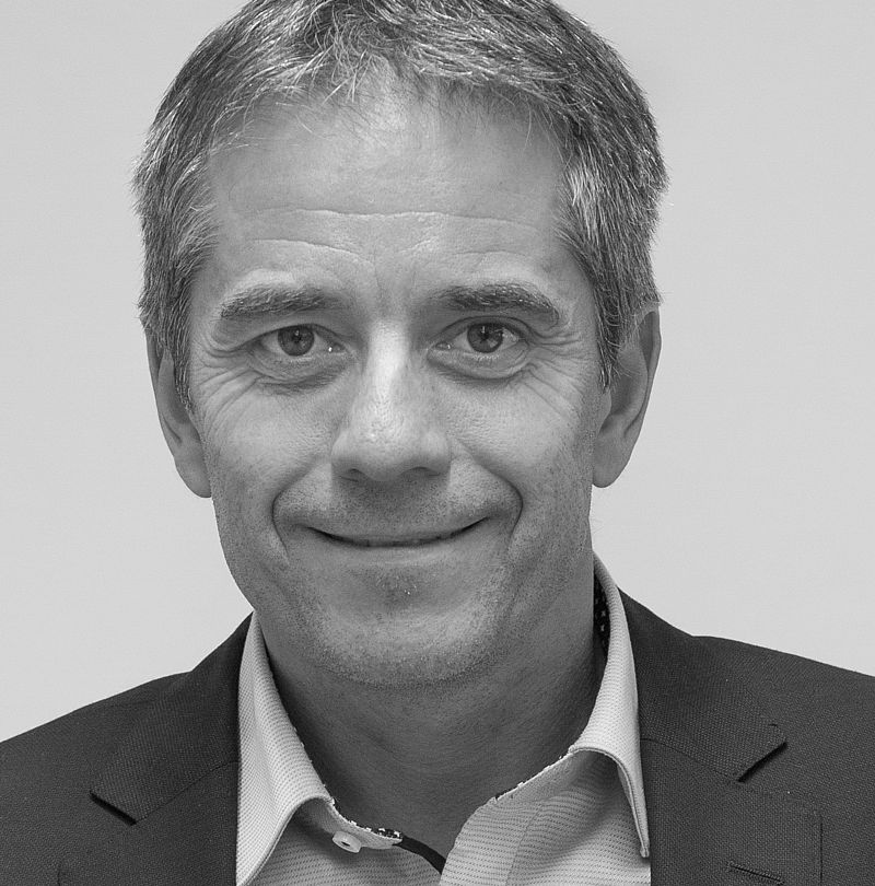 Michael Mayr, TechnoAlpin Mitarbeiter, Schwarz-Weiß-Portrait mit warmem Lächeln, graumeliertem Haar und dunklem Sakko