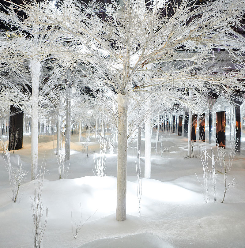 Verschneite Indoor-Winterlandschaft mit beleuchteten Bäumen dank TechnoAlpin SNOWROOM