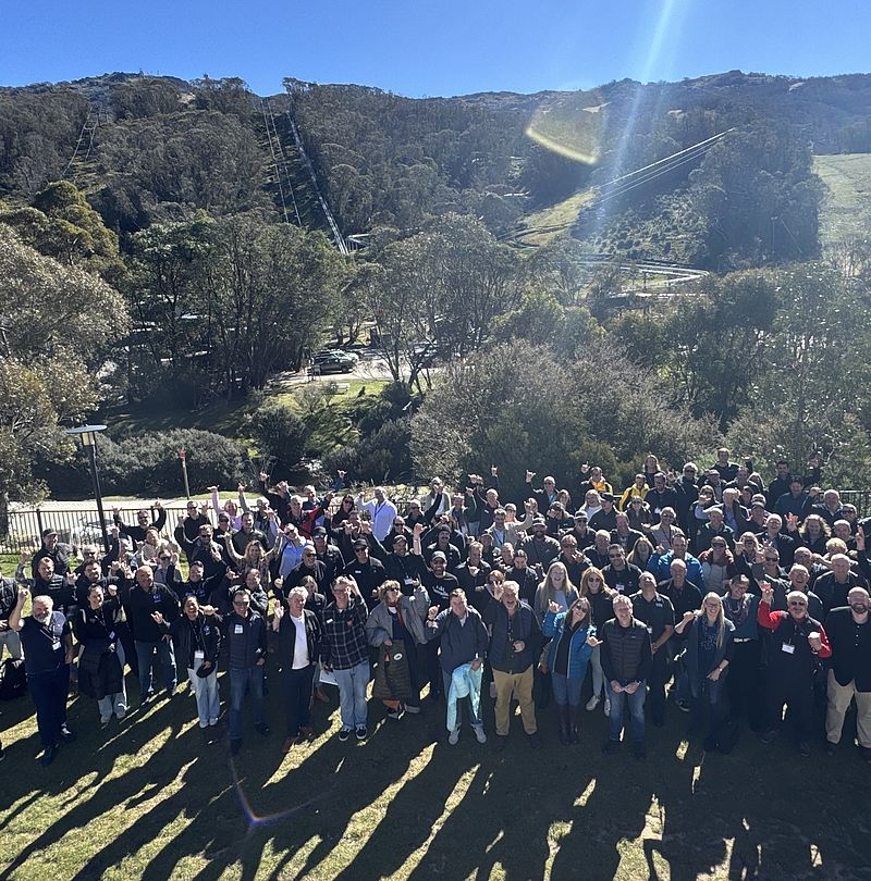 Großes Gruppenfoto der Snow Summit Australia Teilnehmer vor Bergkulisse mit Skiliften