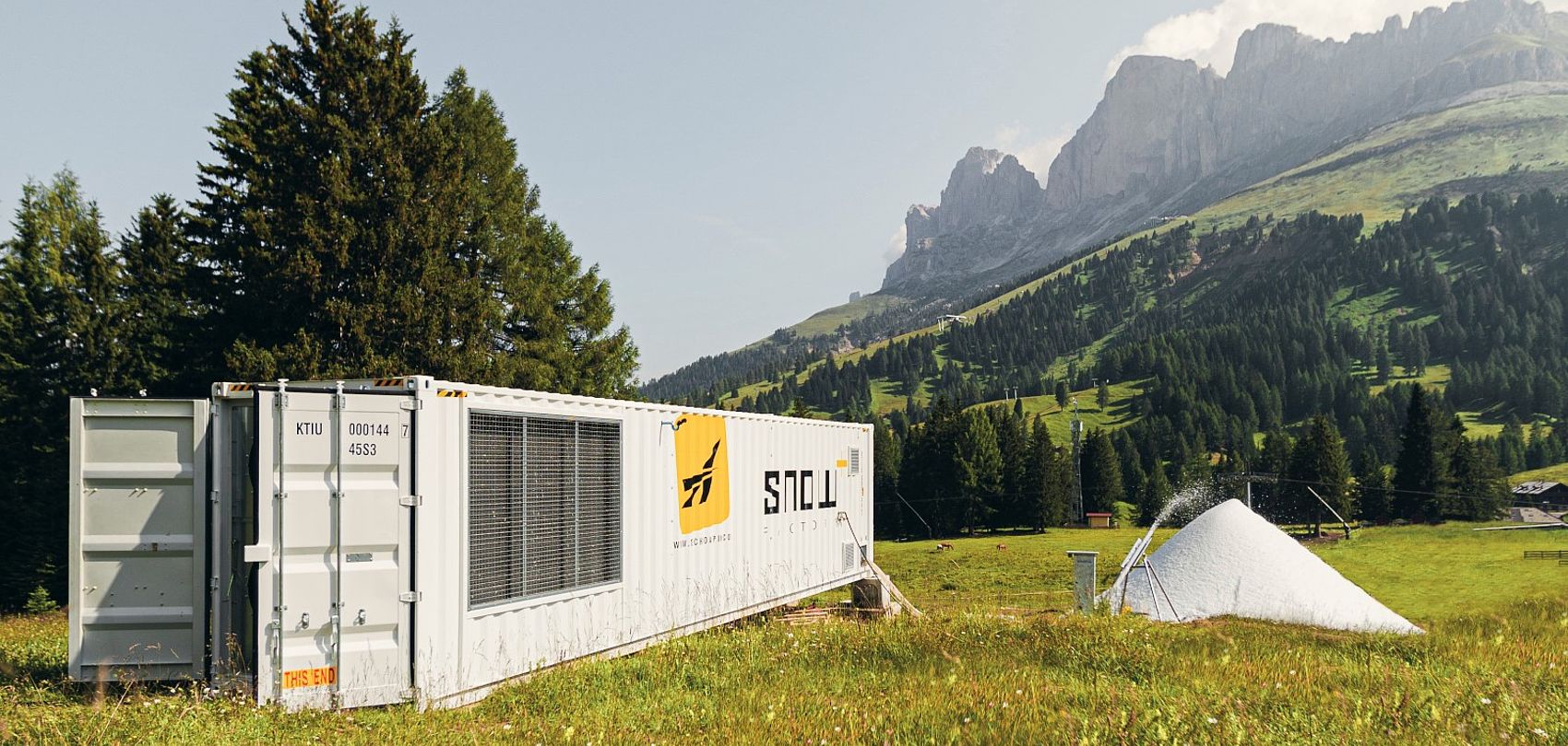 Container TechnoAlpin SnowFactory sur pré alpin produisant de la neige devant les Dolomites