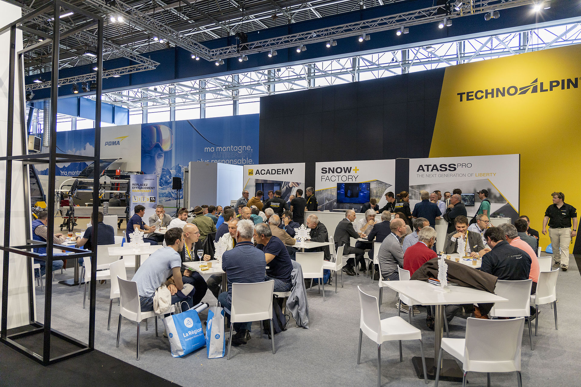Overview of busy TechnoAlpin trade show stand with ATASS Pro, Academy and Snow Factory areas.
