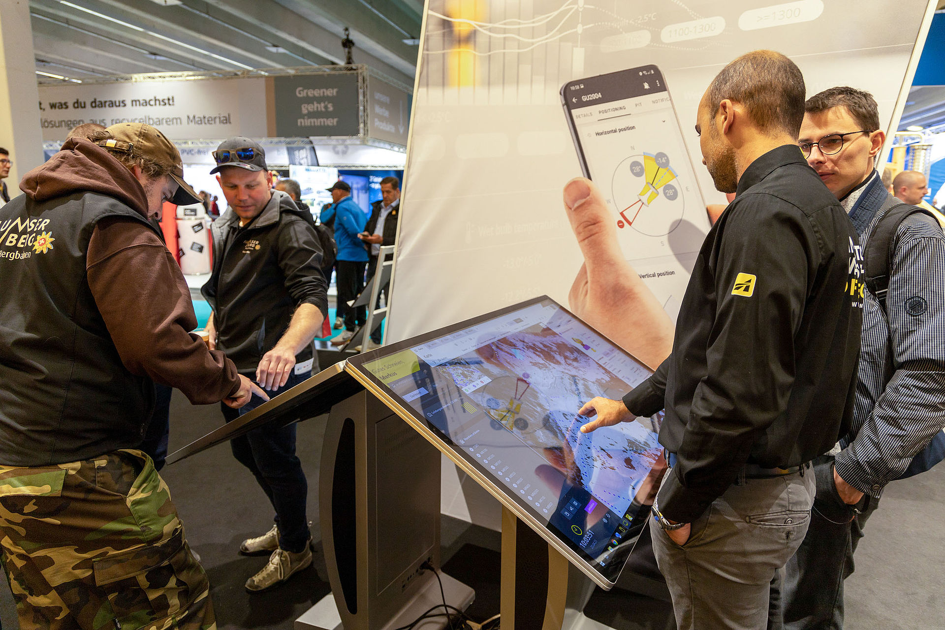 Interaktiver Touchscreen-Kiosk am TechnoAlpin Interalpin-Stand mit Beschneiungsapp, Karte und Positionierungsdaten, Mitarbeiter demonstriert