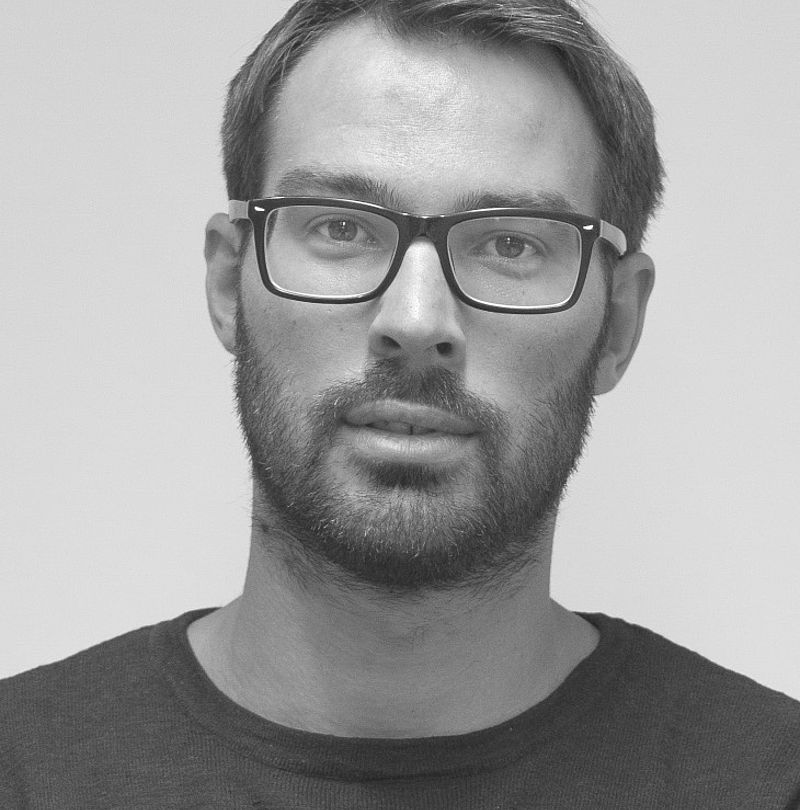 Daniel Neulichedl, TechnoAlpin Mitarbeiter, Schwarz-Weiß-Portrait mit kurzem Haar, schwarzer Brille und neutralem Ausdruck in dunklem T-Shirt