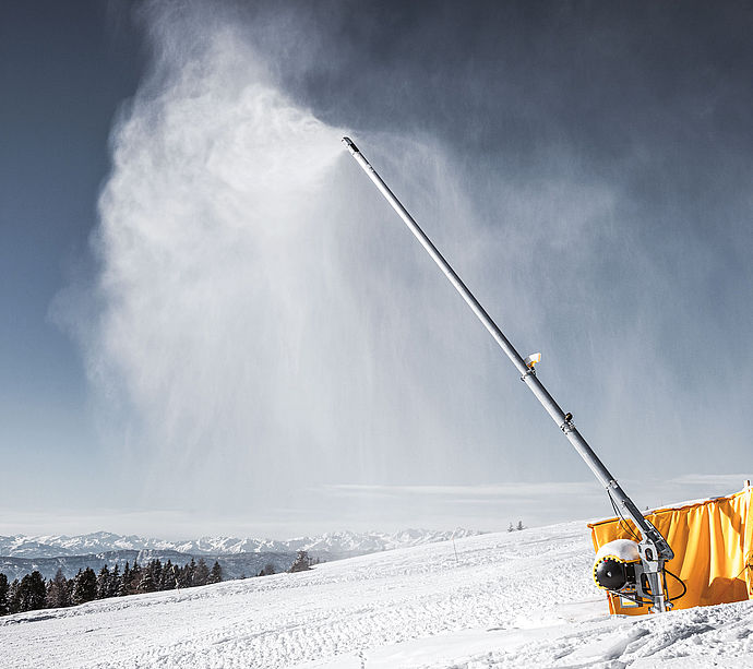 TechnoAlpin Schneilanze im Einsatz auf der Skipiste mit Alpenpanorama im Hintergrund