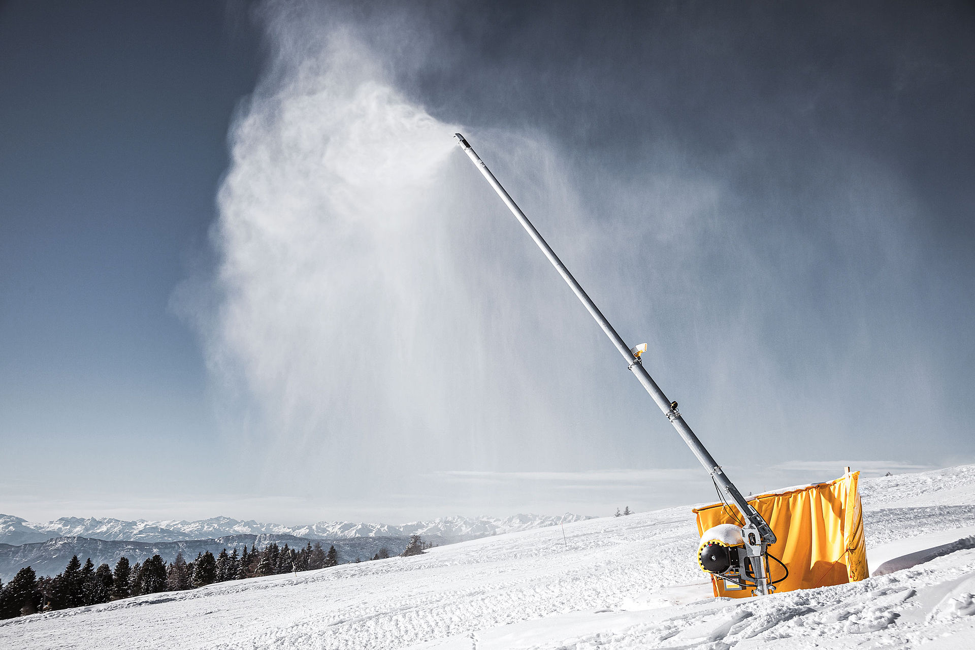 TechnoAlpin Schneilanze im Einsatz auf der Skipiste mit Alpenpanorama im Hintergrund