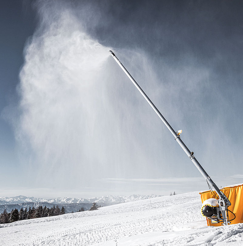 Lancia da neve TechnoAlpin in funzione sulla pista da sci con panorama alpino