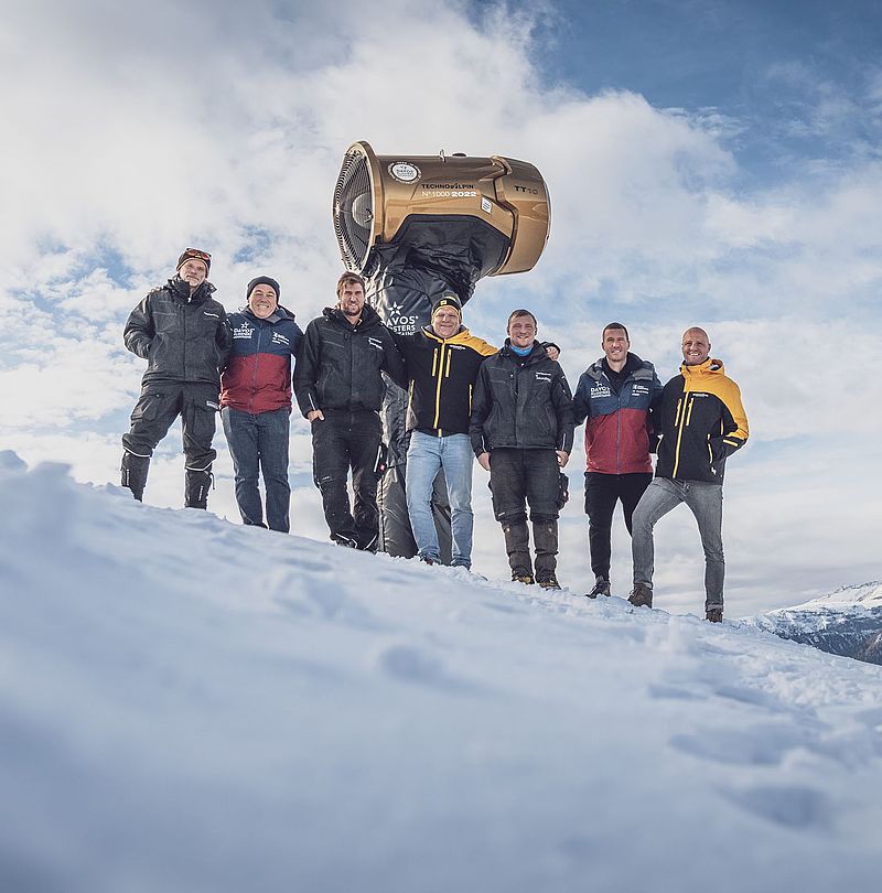 Group on snowy slope with gold TechnoAlpin TT10 No.1000 (2022), milestone delivery to Davos Klosters Mountains