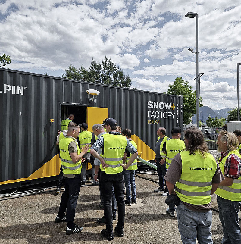 Kundenbesuch an SnowFactory Container mit Gruppe in Warnwesten