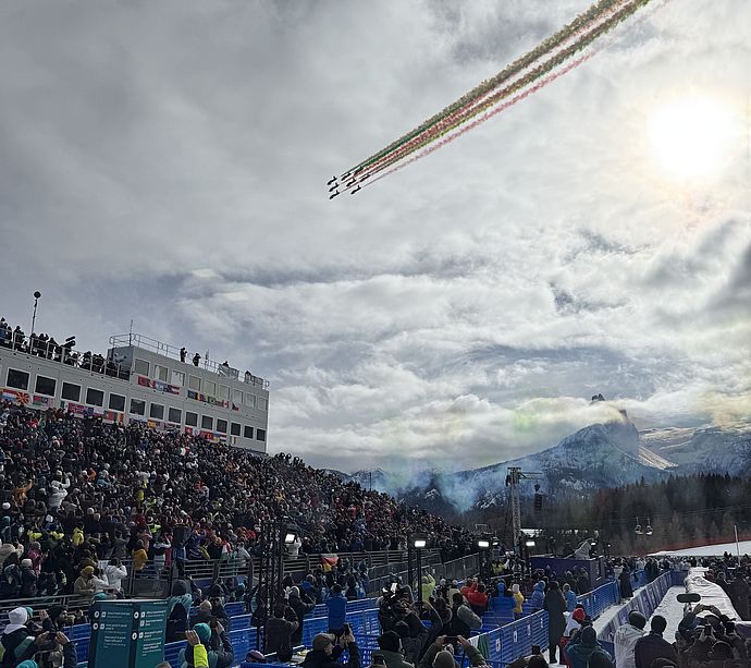 Italian Frecce Tricolori aerobatic team with green-white-red smoke over packed Olympic stadium