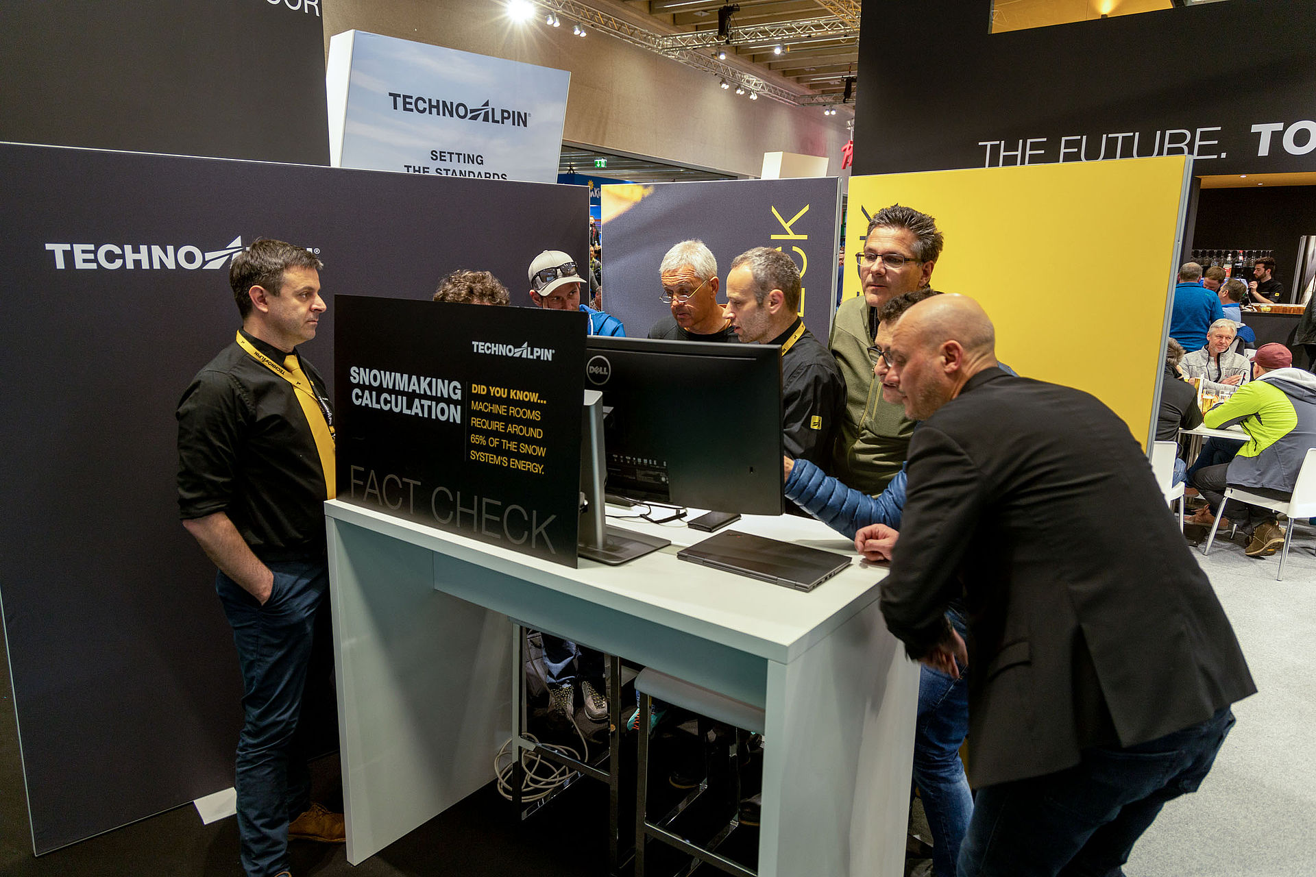 Besucher am TechnoAlpin Fact Check-Stand auf der Interalpin mit Dell-Monitor, der Beschneiungsberechnungen und Energieverbrauch zeigt