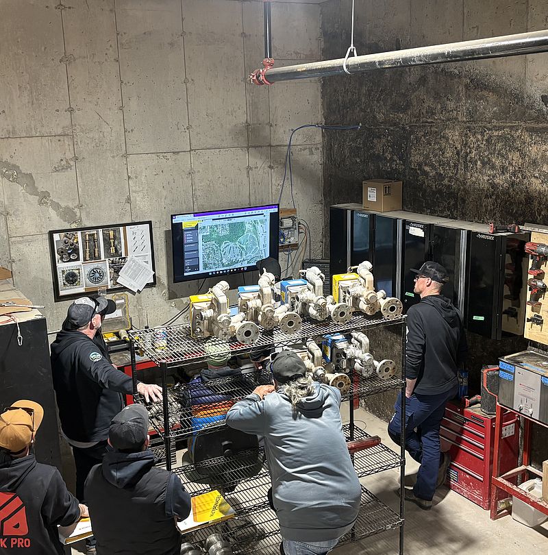 [Translate to USA:] Academy on Tour participants analyze the components and control data of the snowmaking system at the Craigleith Ski Club.