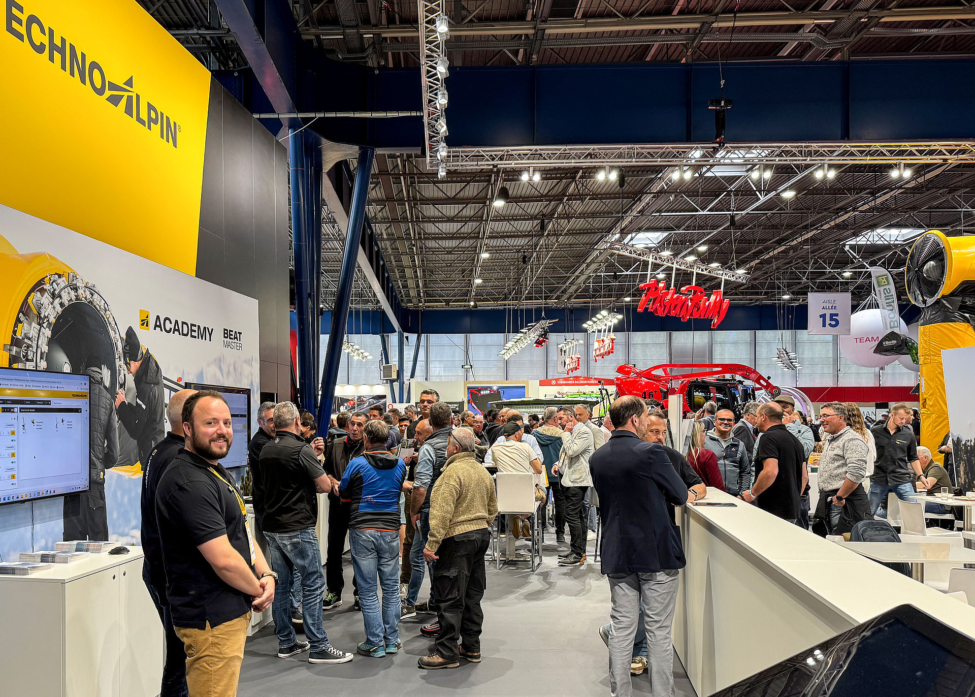 Überblick TechnoAlpin Messestand mit Academy-Bereich, Besuchern und Pistenbully im Hintergrund