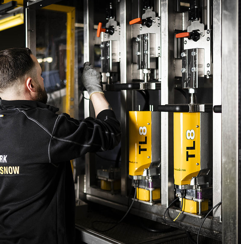 TechnoAlpin Mitarbeiter montiert gelbe TL8 Schneeerzeuger-Komponenten in Produktionshalle