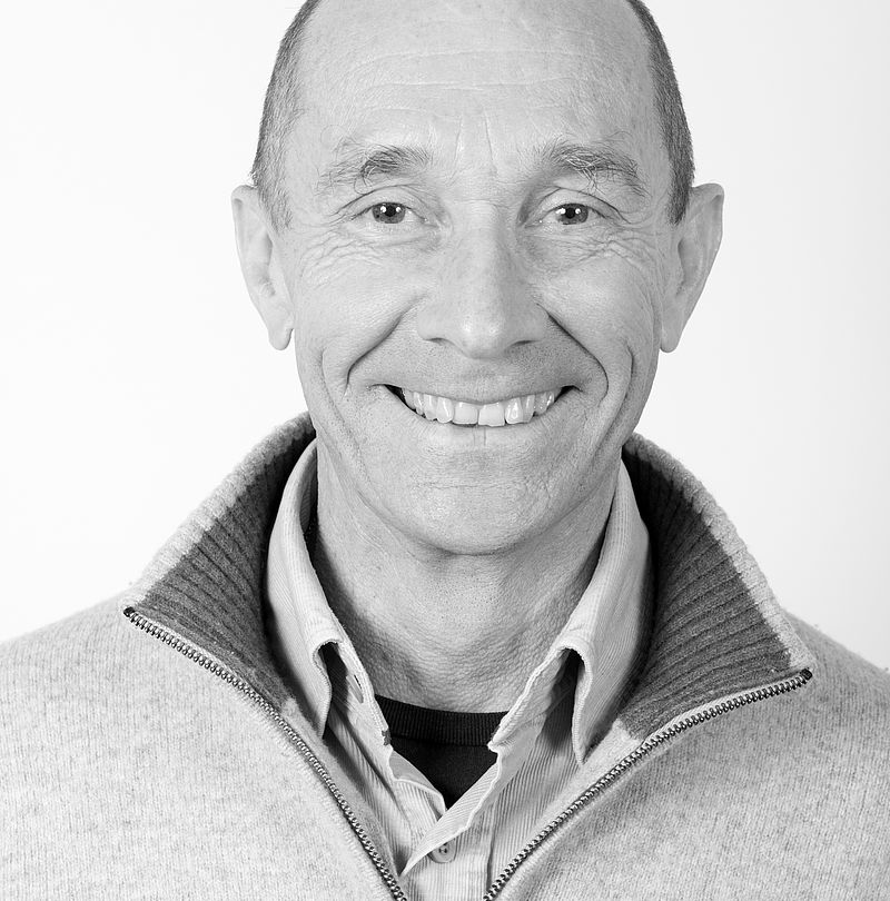 Laurent Guilleminot, TechnoAlpin Mitarbeiter, Schwarz-Weiß-Portrait mit Glatze, herzlichem Lächeln und hellgrauem Stehkragenpullover