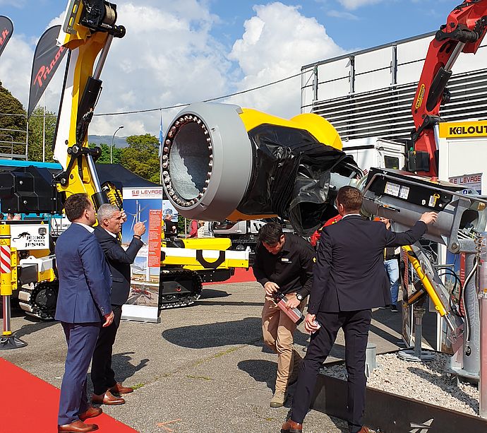 Outdoor presentation of TechnoAlpin snow gun with crane next to other machines under blue sky.