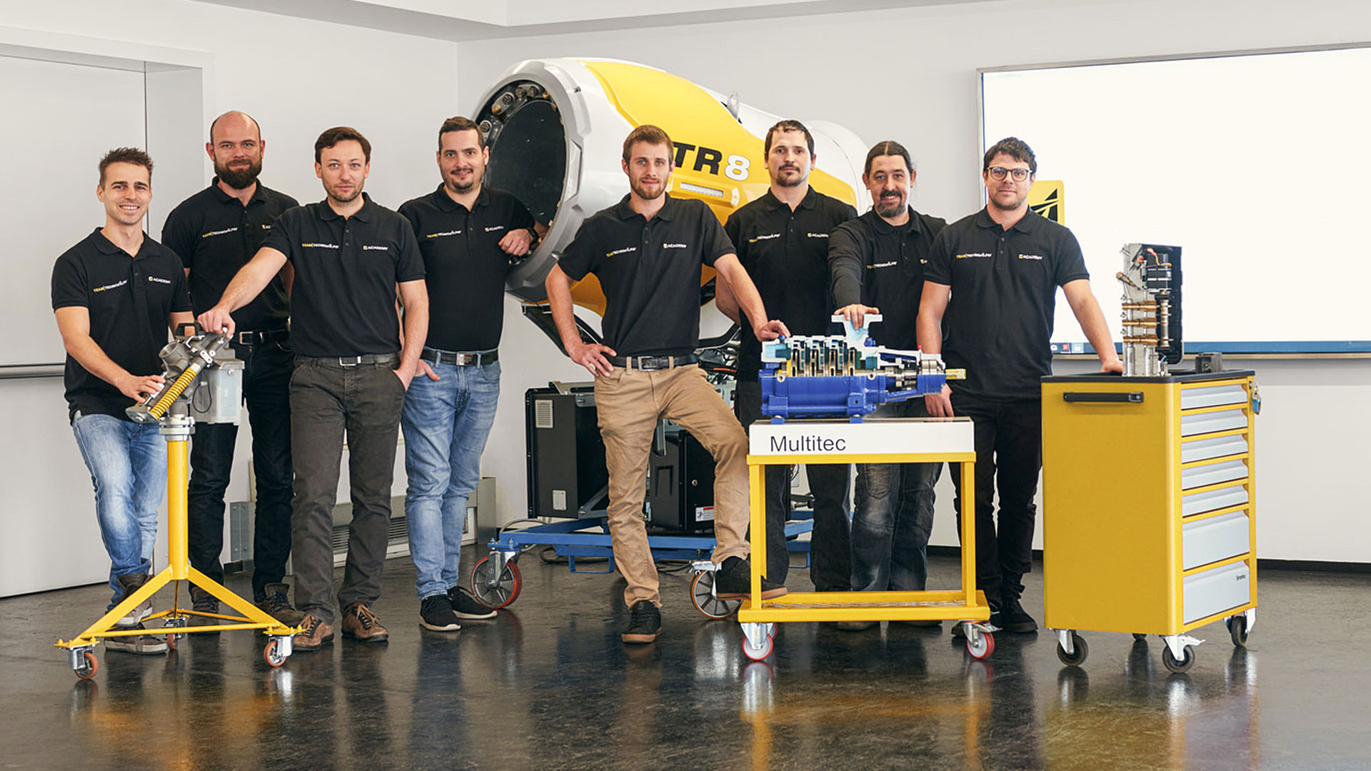 Team TechnoAlpin Academy in posa davanti a un cannone da neve TR8 con componenti didattici