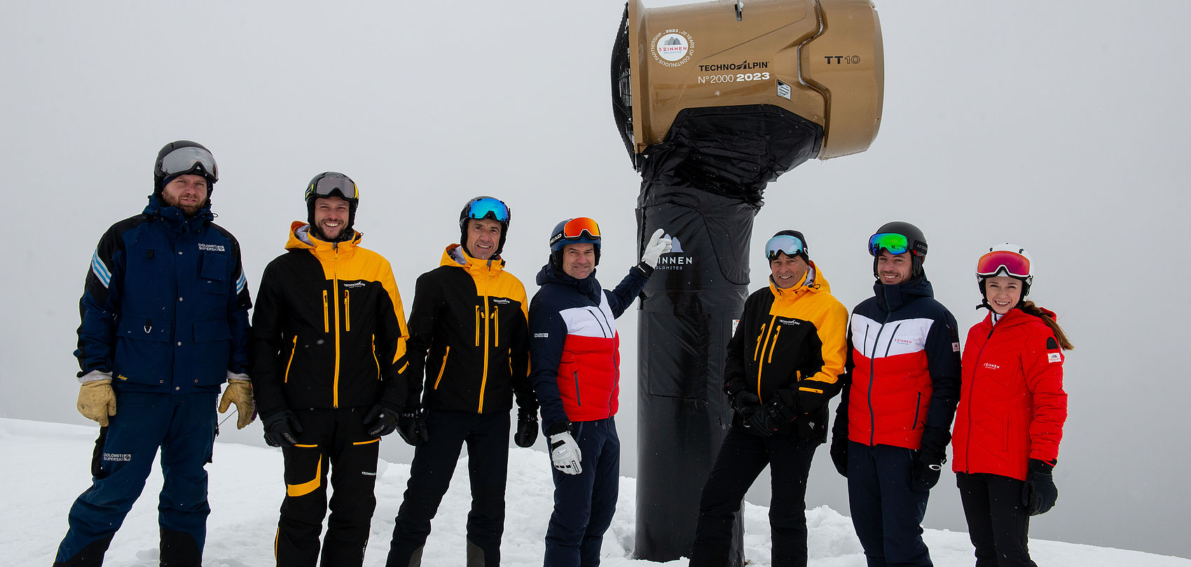 Goldene TT10 Jubiläumsschneekanone N°2000 vor verschneitem Dolomitenpanorama mit Wolkenhimmel