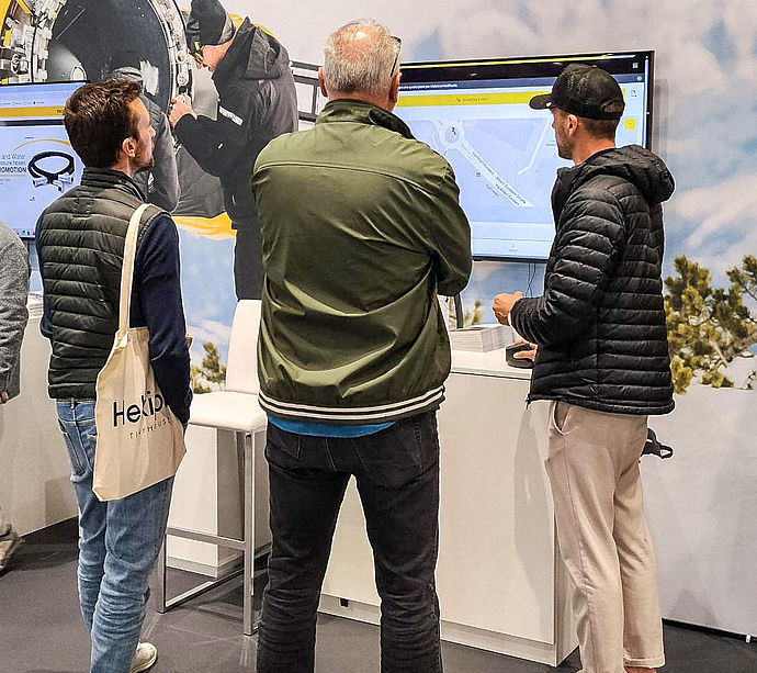 Messebesucher am TechnoAlpin Stand vor Academy- und Beatmaster-Bildschirm auf der Mountain Planet
