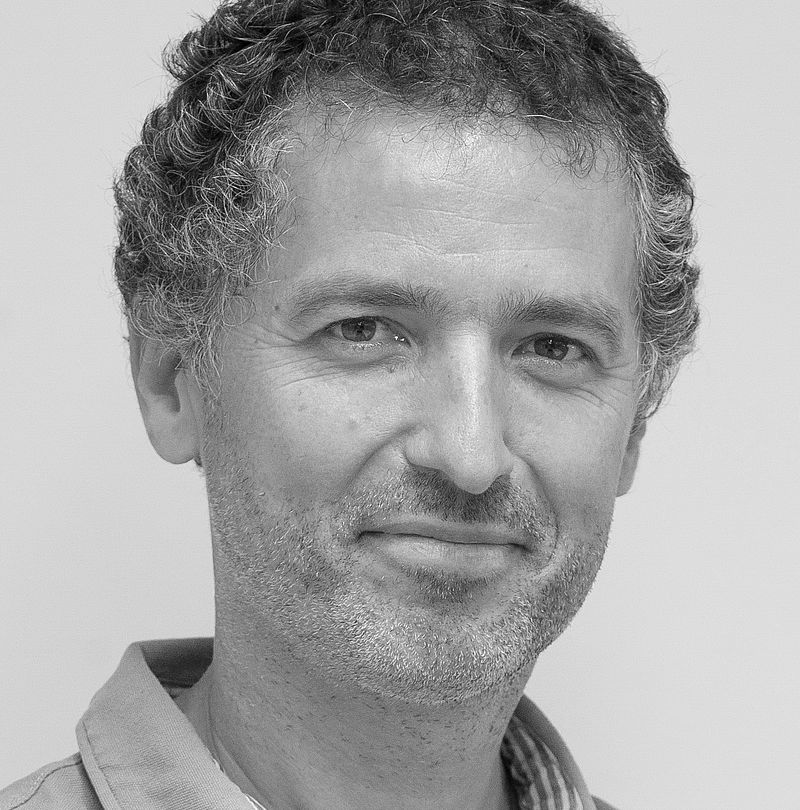 Philippe Ronin, TechnoAlpin Mitarbeiter, Schwarz-Weiß-Portrait mit freundlichem Lächeln und kurzem dunklem Lockenhaar
