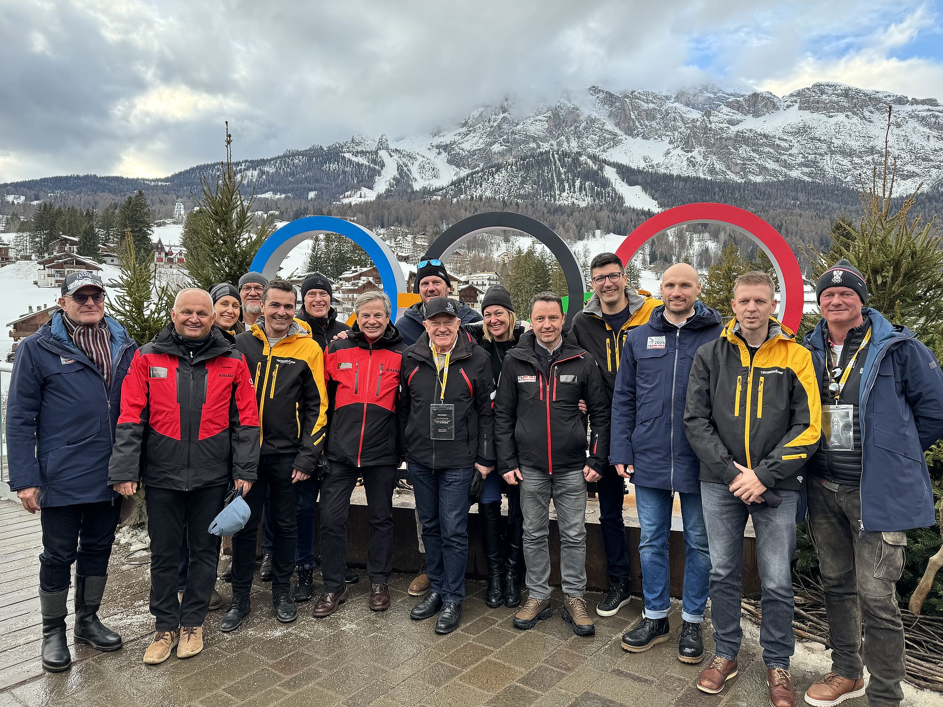 Group photo in front of Olympic rings in Cortina d'Ampezzo with snowy mountain scenery