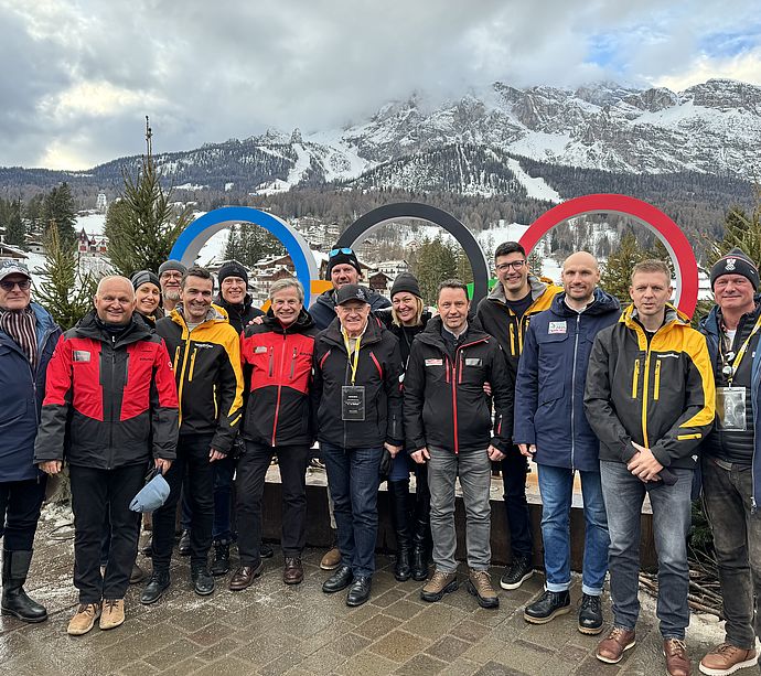 Group photo in front of Olympic rings in Cortina d'Ampezzo with snowy mountain scenery
